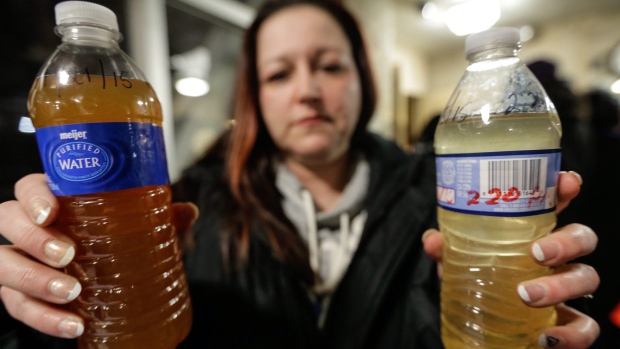Une habitante de Flint, Michigan tient des bouteilles d'eau remplies de l'eau contaminée par le rivière Flint